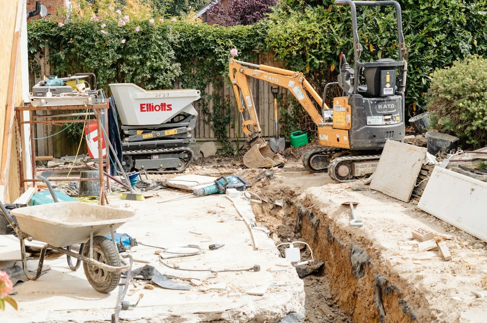 Mini-pelle et tranchée de terrassement sur un chantier de piscine dans un jardin